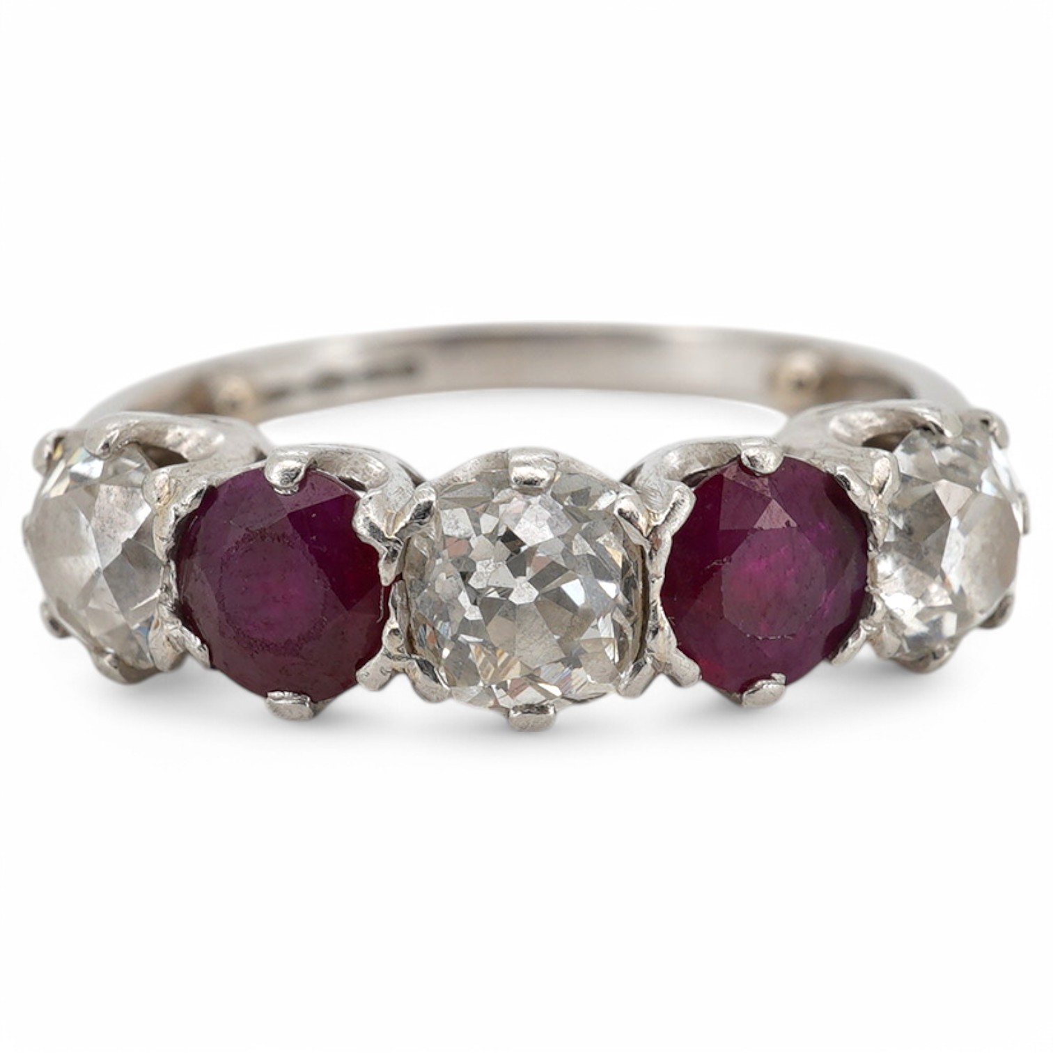 A ruby and diamond five-stone ring, set with an alternating sequence of antique cushion-shaped diamonds totalling approximately 1.50 carats, spaced with circular-cut rubies, mounted in platinum, size M (sizing beads), Br